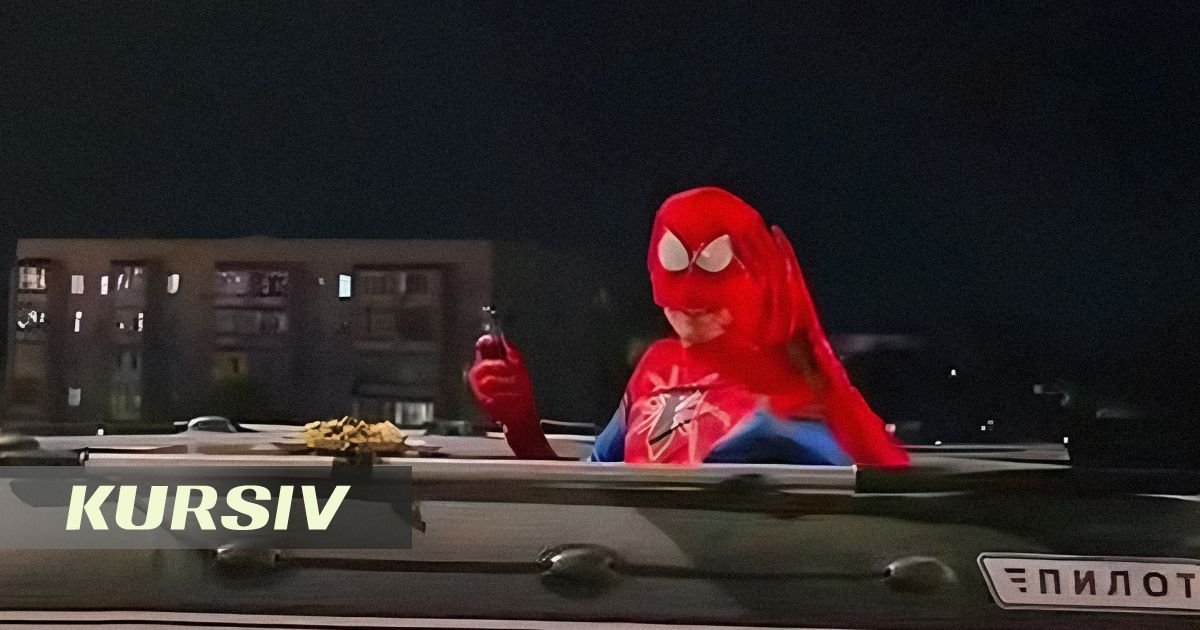 Mitsubishi Pajero with a person in a Spider-Man costume riding in a trailer over a suspension bridge in Semey